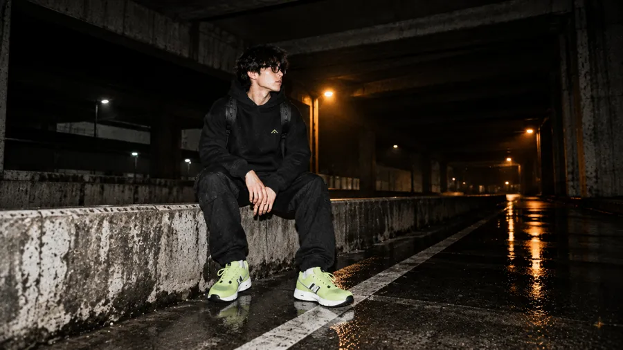 Model duduk di pembatas beton, sepatu lime.